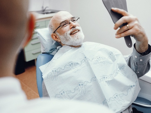 a man looking in a handheld mirror and smiling