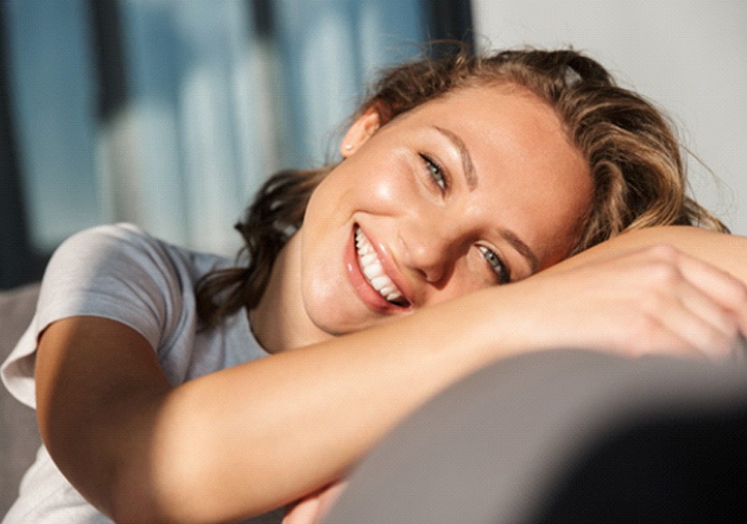Woman resting head on couch and smiling