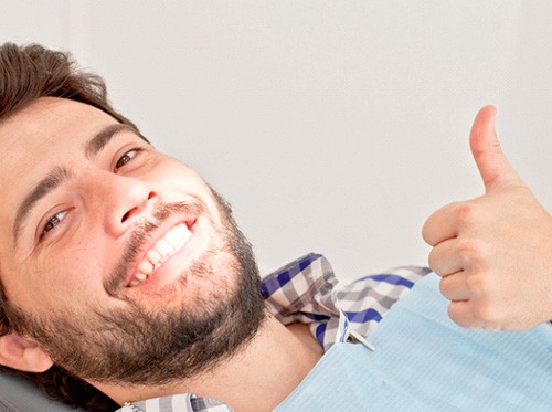 Man with beard giving thumbs up in dental chair