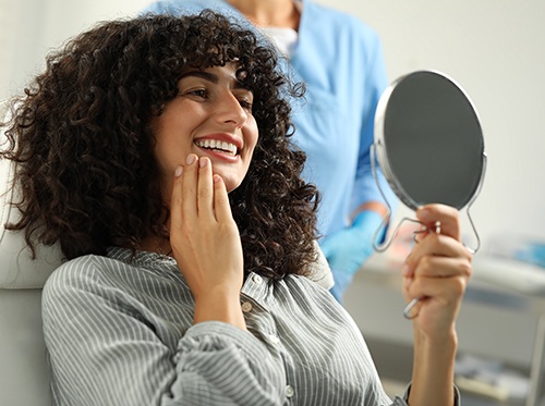 Cosmetic dentistry patient admiring her smile in the mirror