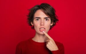 Young woman holding exposed gum w/ gum disease.